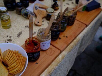 Jars of jams and spreads with crackers on a table.