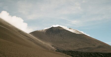 A smoking volcano under a cloudy sky